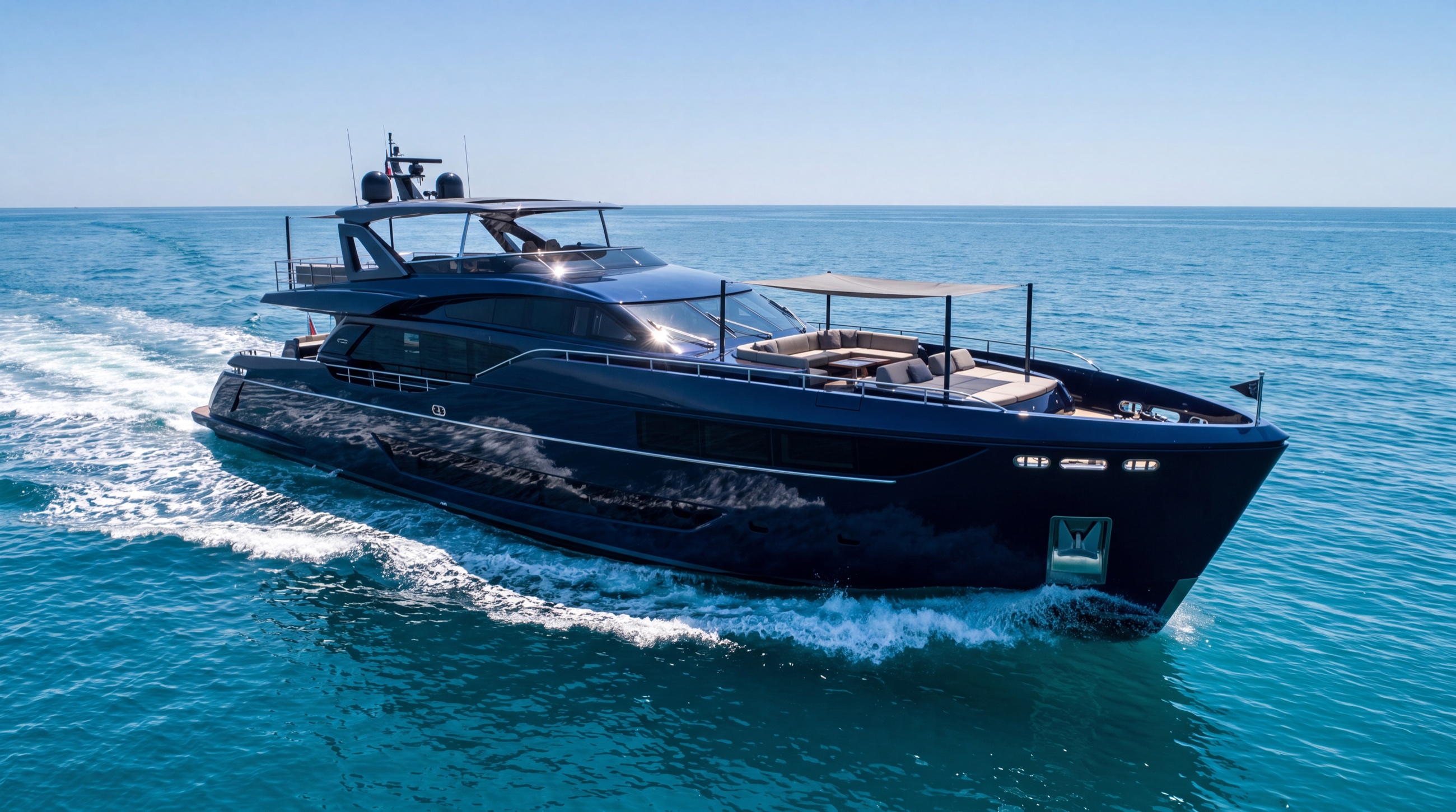 A sleek modern sport motor yacht with a dark navy hull cruising turquoise water